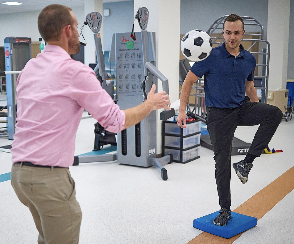 Patient and therapist performing therapy with a soccer ball