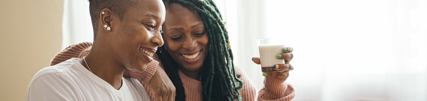 Two African American women looking at a laptop while enjoying coffee.